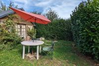 a table with a red umbrella and a chair at Gîte de charme - Normandie in Breteuil-sur-Iton