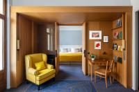 a living room with a yellow chair and a bedroom at Hôtel Royal in Évian-les-Bains