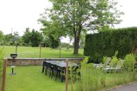 a table and chairs in a garden with a field at La Gendarmerie in Chevron