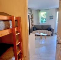 a room with a bunk bed and a living room at 100 m de la plage - Les Cigales de Mer - Studio Cabine - Parking in Le Grau-du-Roi