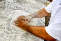 Ein Mann bereitet eine Pizza auf einer Küchentheke zu. in der Unterkunft Baia Degli Aranci Suite & Apartments in Vieste