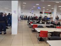 een cafetaria met tafels en rode stoelen en mensen bij Sulimen Camp in Tengiz