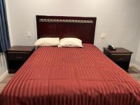 Una cama grande con un edredón rojo y dos mesitas de noche. en Budget inn Whittier, en Whittier