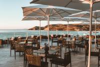 Un restaurante con mesas y sillas con vista al mar. en Apollo Resort, en Agia Marina Aegina