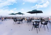 grupa stołów i krzeseł z parasolami na dachu w obiekcie GTA HOTEL IKEJA w mieście Ikeja