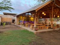 a pavilion with wooden tables and potted plants at Alwi Villa Gili Trawangan in Gili Trawangan
