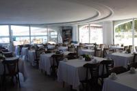 ein Restaurant mit weißen Tischen und Stühlen und Fenstern in der Unterkunft New Casablanca Praia Hotel in Paulista