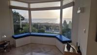 a room with a large window with a view of the ocean at Manava Villa vue mer et Mont Saint Michel piscine intérieure in Saint-Jean-le-Thomas