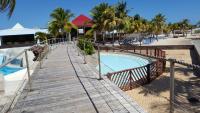 a wooden walkway leading to a pool at a resort at Le Cosy - Studio spacieux, équipé, proche Plage &amp; Piscine, au Manganao in Saint-François