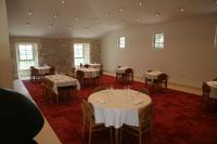 Un comedor con mesas y sillas blancas y ventanas. en Château Lecusse - La Grande Roche - Hôtel, Spa, Boutique & Restaurant, en Broze