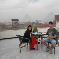 a man and a woman sitting at a table on a roof at Eagles Pyramids View in Cairo