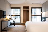 a bedroom with a bed and a desk and two windows at CHECK inn Taipei Songjiang in Taipei
