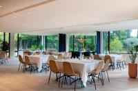 a banquet hall with white tables and chairs and windows at Hilton Garden Inn Marseille Provence Airport in Marignane