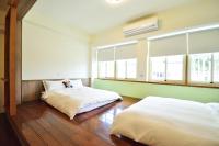 two beds in a room with two windows at Jamie home stay in Taitung City