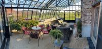 a patio with a table and chairs in a greenhouse at B&amp;B - Ter Douve in Dranouter