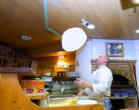 un uomo in piedi in una cucina che prepara il cibo di La Locanda a Livigno