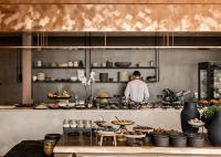 Um homem de pé numa cozinha a preparar comida. em Acro Suites - A Wellbeing Resort em Agia Pelagia
