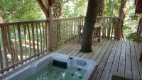 a hot tub on a deck with a tree at Cabane perchée luxe avec jacuzzi Domaine du Marais Maisse in Maisse