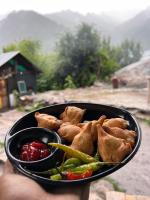 uma pessoa segurando uma tigela de comida com vegetais em Old Brahma Homestay em Kalgha