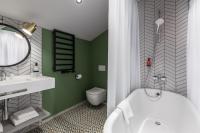 a bathroom with a white tub and a green wall at Konventa Sēta Hotel Keystone Collection in Riga