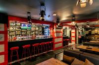 a bar with red walls and red stools at Konventa Sēta Hotel Keystone Collection in Riga