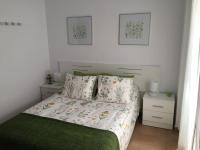 a bedroom with a bed with a green blanket and pillows at San Juan Apartamento in Jerez de la Frontera