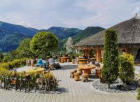 eine Terrasse mit Tischen und Stühlen mit Bergen im Hintergrund in der Unterkunft Apartmánový dom v Panoráma Parku in Nezbudská Lúčka