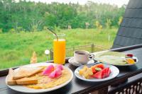 un tavolo con due piatti di cibo e un bicchiere di succo d'arancia di The Pyramid Ubud River Villas a Gianyar
