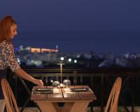 een vrouw die naast een tafel op een balkon staat bij Asterias Village in Chersonissos