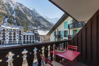 a red table and chairs on a balcony with mountains at Chamonix Sud - Forclaz 304 - Happy Rentals in Chamonix