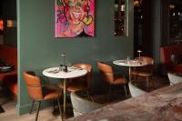 Un restaurante con dos mesas y sillas y un cuadro. en The Address Glasgow, en Glasgow
