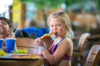 a little girl eating a slice of pizza at Timber Ridge Lodge and Waterpark in Lake Geneva