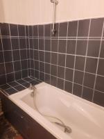 a bath tub in a bathroom with black tiles at La Chambre Saint Jacques &amp; Rennes in Saint-Jacques-de-la-Lande