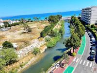 a river with cars parked next to a road and the ocean at Le Chaville in Cagnes-sur-Mer