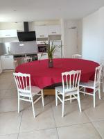a dining room table with a red tablecloth and white chairs at Domaine de kerbillec in Theix