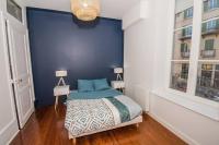 a bedroom with a blue wall with a bed and two windows at T3quartier Rsidentielcosyfamilleamis in Mâcon