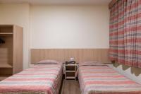 a room with two beds and a nightstand between them at DELPLAZA Timbiras São Paulo in São Paulo