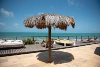 Un patio con una sombrilla de paja y una mesa y sillas. en Pousada Vila Canoa, en Canoa Quebrada