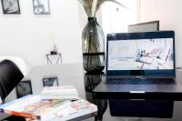 a laptop computer sitting on a desk with a vase at Grand &amp; Lumineux T2 au Coeur de Monplaisir • Métro à 2’ • Parking Privé in Lyon