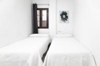 two beds in a room with white walls at Palacio de Luja in El Puerto de Santa María