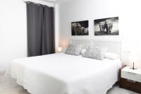 a white bedroom with a white bed and two pictures on the wall at Palacio de Luja in El Puerto de Santa María