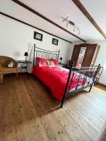 a bedroom with a bed with red sheets and a wooden floor at Maison 6 personnes avec piscine in Le Conquet