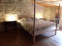a bedroom with a bed in a stone walled room at L&#39;Armandière, maison de caractère où règne calme et sérénité. in Pézenes-les-Mines