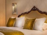 a bedroom with a bed with white pillows and a mirror at Hotel Papadopoli Venezia - MGallery Collection in Venice