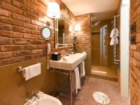 a bathroom with a white sink and a brick wall at Hotel Papadopoli Venezia - MGallery Collection in Venice
