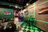 um restaurante com iluminação verde e mesas e cadeiras em Wescott Hotel no Dubai