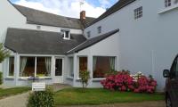 a white house with pink flowers in the yard at Hotel au Moyne De Saire in Réville