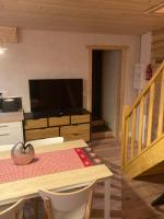 ein Wohnzimmer mit einem Tisch, einem TV und einer Treppe in der Unterkunft Maison Boutxy Le Clos des Ours in Matemale