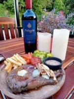 een bord vlees en frietjes en een fles wijn bij Mountain View Guest House in Phatthalung