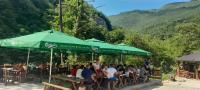 um grupo de pessoas sentadas em mesas sob um guarda-chuva verde em Rafting Camp Encijan em Foca